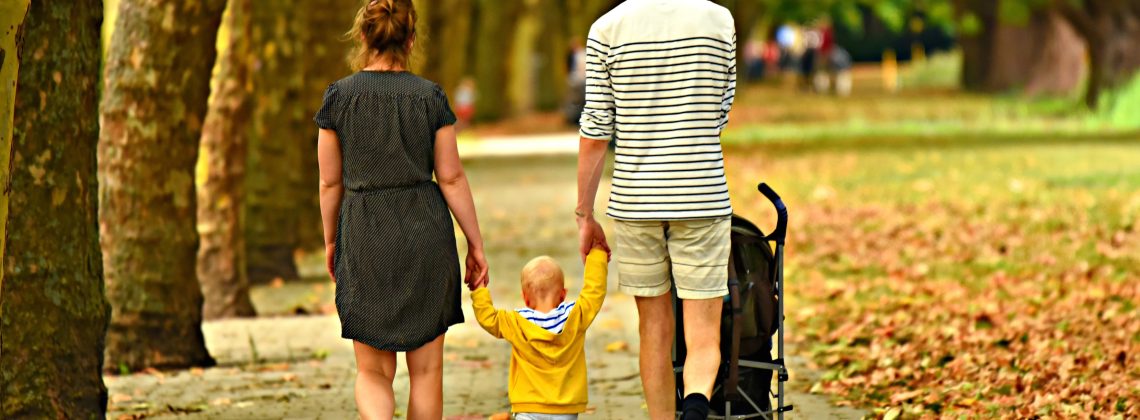Rodzice spacerujÄ…cy z maÅ‚ym dzieckiem w parku w ramach wspÃ³lnego spÄ™dzania wolnego czasu